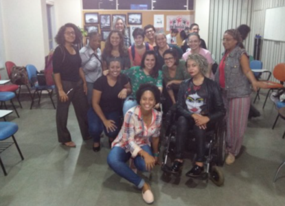 Quinze mulheres, brancas e negras posam para foto dentro de um espaço de trabalho do curso.